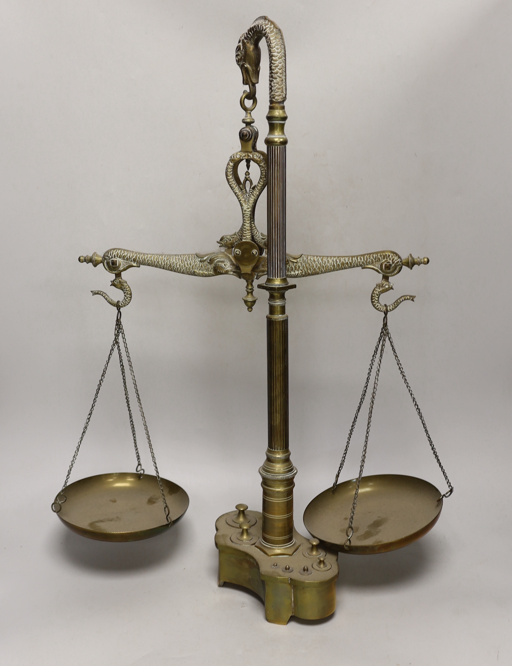 A set of dolphin decorated brass scales and a set of weights, 61cm high